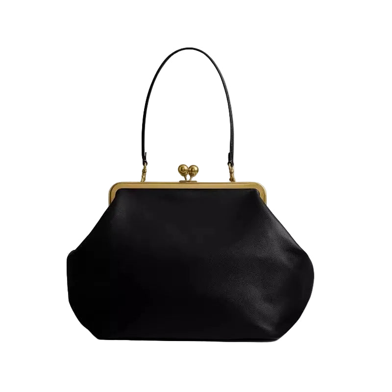 Black handbag with gold clasp on a light gray background