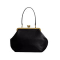 Black handbag with gold clasp on a light gray background